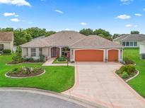 Charming single-story home with a three-car garage, manicured lawn, and colorful landscaping at 1804 Estafana Way, The Villages, FL 32159