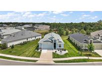 Beautiful aerial view of a single-Gathering home with lush green landscaping, a driveway, and neighboring houses at 1966 Wallingford Loop, Mount Dora, FL 32757