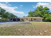 Charming single-story home featuring a large driveway, well-manicured lawn, and mature shade trees at 23519 State Road 44, Eustis, FL 32736