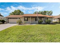 Charming single-story home with a well-maintained lawn, a two car garage, and appealing curb appeal at 26535 Deuce Ct, Leesburg, FL 34748