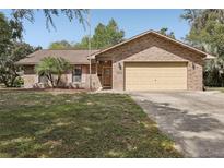 Charming brick home with a well-manicured lawn and attached two-car garage at 35138 Silver Oak Dr, Leesburg, FL 34788