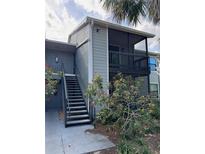 Two-story condo building with gray siding, black railings, and a stairwell leading to the upper units at 3748 Idlebrook Cir # 202, Casselberry, FL 32707