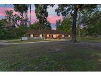 Charming home featuring a stone facade, complemented by lush landscaping and mature trees at sunset at 400 Sw 35Th St, Ocala, FL 34471