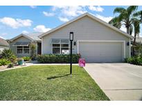 Charming single-story home featuring a well-manicured lawn and a two-car garage at 419 Aldama Ave, The Villages, FL 32159