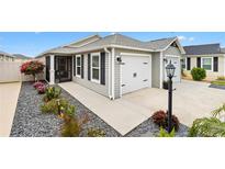 Charming single-story home featuring a two-car garage, landscaped front yard, and a screened-in porch at 5726 Leboeuf Ln, The Villages, FL 32163