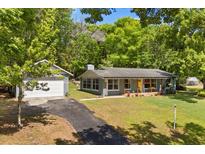 Charming single-story home with lush landscaping, detached garage, and welcoming yellow front door at 7115 Lake Ola Dr, Mount Dora, FL 32757
