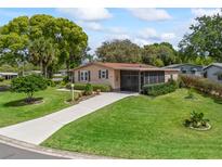 Charming single-story home with well-maintained lawn, mature trees and inviting screened-in porch in a sunny setting at 1003 Parker Pl, Lady Lake, FL 32159