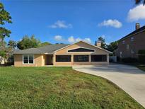 Tan single-story home featuring a well-maintained lawn and a concrete driveway at 2037 Lakeshore Dr, Mount Dora, FL 32757