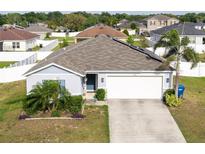 Charming single-story home featuring a two-car garage, well-manicured landscaping, and solar panels at 2256 Gladiolus Ln, Mascotte, FL 34753