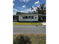 Charming single-story home featuring a well-maintained lawn and an American flag on a sunny day at 313 Palo Verde Dr, Leesburg, FL 34748