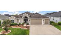 Charming single-story home with a well-manicured front yard and a three car garage at 3354 Truluck Pl, Oxford, FL 34484