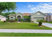 Landscaped front yard and exterior of a single-story home with stone accents and a two-car garage at 3440 Tumbling River Dr, Clermont, FL 34711