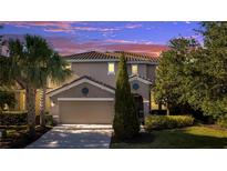 Charming two-story home showcasing a well-manicured lawn, mature trees, and a spacious two-car garage at 4328 Acorn Ct, Davenport, FL 33837