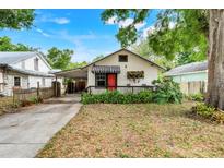 Charming single-story home with a covered porch, bright red door, and lush landscaping at 545 W Cummings St, Lake Alfred, FL 33850
