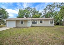 Charming single-story home featuring an attached garage and well-maintained front lawn at 74 Stone Haven Ct, Leesburg, FL 34788