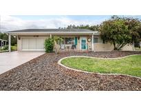 Charming single-story home with a well-manicured lawn, inviting front porch, and attached garage at 10689 Se 174Th Loop, Summerfield, FL 34491