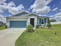 Charming single-story home with well-maintained lawn, blue accents, and two-car garage at 1688 Littleleaf Boxwood Loop, Mascotte, FL 34753