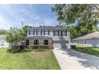 Charming two-story home with a well-manicured lawn and grey exterior paint, offering a welcoming curb appeal at 1704 Hoofprint Court, Fruitland Park, FL 34731