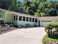 Charming home featuring an attached garage, large driveway, and ample greenery surrounding the property at 1765 Hilltop Dr, Mount Dora, FL 32757