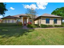 Charming single-story home featuring a well-manicured lawn and a welcoming front entrance with red door at 39705 Grove Hts, Lady Lake, FL 32159