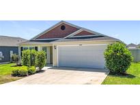 Charming single-story home with a two-car garage, well-maintained lawn, and lovely landscaping at 449 Gilson Loop, The Villages, FL 32163