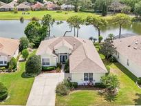 A charming single-story home boasts lush landscaping and a serene lake view with golf course backdrop at 8043 Pine Hollow Dr, Mount Dora, FL 32757