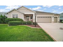 Charming home featuring a well-manicured lawn, mature landscaping, and a two-car garage at 879 Lucky Ln, The Villages, FL 32162