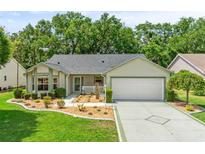 Charming single-story home with a well-manicured lawn, lush landscaping, and a two-car garage at 1061 Soledad Way, The Villages, FL 32159