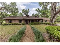 Charming single-story brick home with a well-manicured lawn, mature trees, and a inviting walkway at 12196 Ne 4Th Pl, Oxford, FL 34484