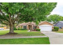 Inviting single-story home with lush front lawn, mature tree, and charming curb appeal at 12846 Brown Bark Trl, Clermont, FL 34711