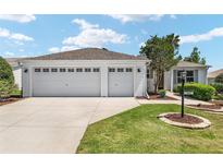 Charming home featuring a two-car garage, well-manicured lawn, and beautiful landscaping at 1502 Blueberry Way, The Villages, FL 32162