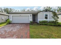 Charming single-story home with a brick driveway, lush lawn, and beautifully landscaped front yard at 28078 Poppy Ct, Leesburg, FL 34748