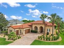 Stunning Mediterranean-style home with a red tile roof, arched entryways, and a meticulously landscaped front yard at 38716 Oak Place Ct, Lady Lake, FL 32159