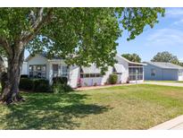 Charming single-story home with mature tree, lush lawn, and well-maintained landscaping at 705 Prado Dr, The Villages, FL 32159