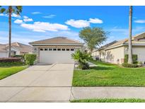 Charming single-story home featuring a well-manicured lawn, stone accents, and a two-car garage at 9081 Saint Andrews Way, Mount Dora, FL 32757