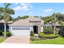 Charming single-story home with a manicured lawn, brick driveway, and a two-car garage surrounded by lush landscaping at 1047 Timbervale Trl, Clermont, FL 34715