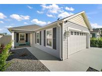 Charming single-story home featuring a two-car garage and well-maintained landscaping under a partly cloudy sky at 1251 Saranac Pl, The Villages, FL 32163