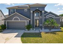 Beautiful two-story home with a well-manicured lawn, gray stucco, and a two-car garage at 13519 Bristlecone Cir, Orlando, FL 32828
