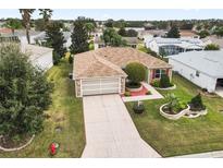 Charming single-story home with a well-manicured lawn, brick accents, and a spacious two-car garage at 1526 Blueberry Way, The Villages, FL 32162