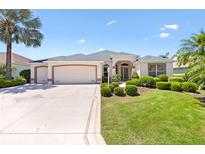 Well-maintained single-story home with manicured lawn, mature palms, and a triple-car garage at 1716 Bugle Ter, The Villages, FL 32162
