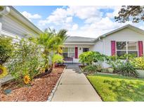 Charming single-story home with well-manicured landscaping, mature trees, and vibrant flower beds lining the walkway at 767 Barbados Pl, The Villages, FL 32162