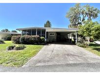 Cozy home featuring a screened-in porch, driveway with covered parking, and well-maintained landscaping at 104 Valencia Cv, Leesburg, FL 34748
