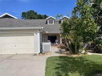 Charming home featuring an attached garage, tidy landscaping, and a cozy front porch with rocking chairs at 106 Baytree Blvd, Tavares, FL 32778