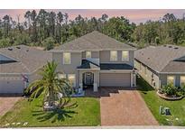 Charming two-story home featuring a well-manicured lawn, brick driveway, and welcoming front entrance at 1128 Cavender Creek Rd, Minneola, FL 34715