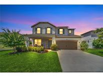 Charming two-story home with lush landscaping, brick accents, and a spacious two-car garage at dusk at 1281 Gatewood Ave, Minneola, FL 34715