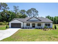 Charming single-story home with a well-manicured lawn, black accents, and an attached two-car garage at 155 W C-466, Lot # 1 W C 466, Oxford, FL 34484