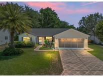 Charming single-story home featuring a well-manicured lawn, mature palm tree, and a patterned driveway at 511 Chula Vista Ave, The Villages, FL 32159