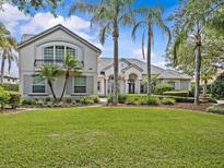 Beautiful home featuring lush green grass, swaying palm trees, manicured shrubs and tasteful landscaping around the property at 5530 Oxford Moor Blvd, Windermere, FL 34786