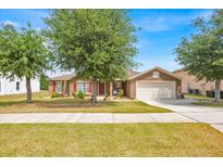Charming single-Gathering home featuring a well-maintained lawn, a two-car garage, and complemented by mature trees at 597 Skyridge Rd, Clermont, FL 34711