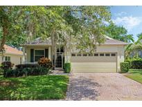 Charming single-story home featuring a brick driveway, attached garage, and mature landscaping with a tree with Spanish moss at 791 Wolf Creek St, Clermont, FL 34711